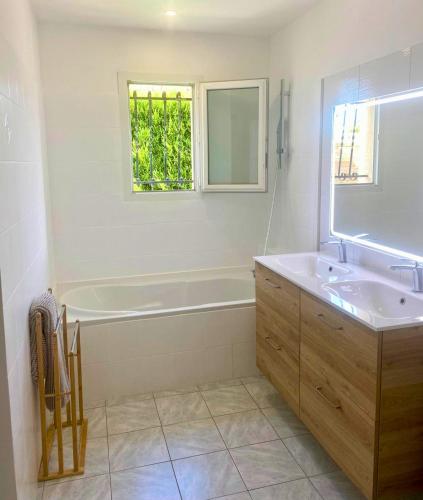 a bathroom with a tub and a sink and a window at Maison cosy avec SPA privatif à 13 min du Futuroscope in Beaumont