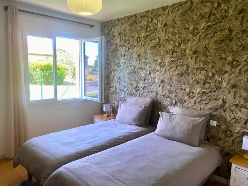 a bedroom with two beds and a stone wall at Maison cosy avec SPA privatif à 13 min du Futuroscope in Beaumont