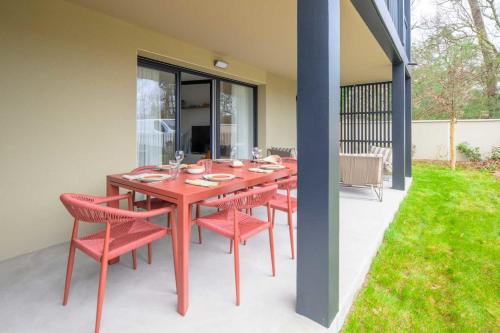 a red dining table and chairs on a patio at Bright House between Ocean and Golf in Moliets-et-Maa