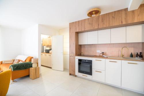 a kitchen with white cabinets and a living room at Bright House between Ocean and Golf in Moliets-et-Maa