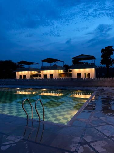 a swimming pool with two metal chairs in front of a building at Marudhar Resort in Chittaurgarh