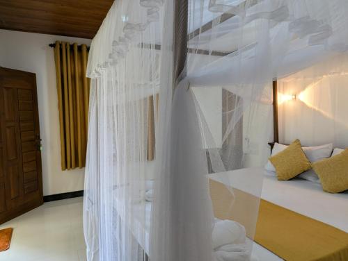a bedroom with a bed with white curtains at Randiwa Homestay in Sigiriya