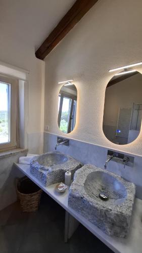two sinks in a bathroom with two mirrors at Stazzu La Vigna Di Maria in Aglientu