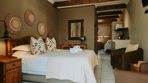 ein Schlafzimmer mit einem großen weißen Bett und einem Stuhl in der Unterkunft Die Herehuis in Beaufort West