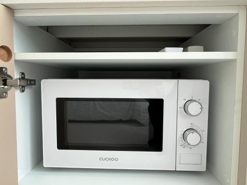 a white microwave in a white shelf at 까사뚜아 Casa Tua in Sokcho