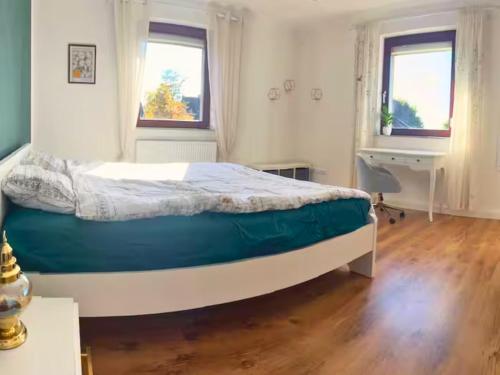 a bedroom with a bed and a desk and two windows at Eifel Moments in Kall