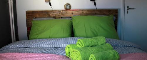 een bed met groene kussens en groene handdoeken erop bij De Tomaat in Aarle-Rixtel