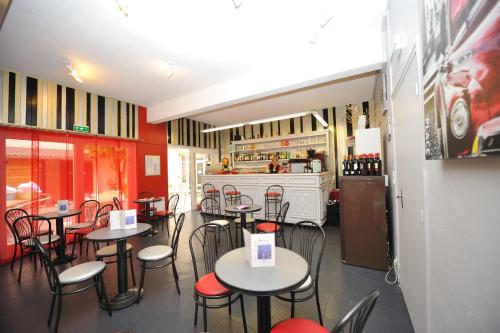 a restaurant with tables and chairs and a refrigerator at Hôtel des Bateliers in La Malène