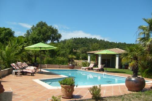 une piscine avec chaises et parasols dans une cour dans l'établissement Le Mas de la Griotte, à Bormes-les-Mimosas