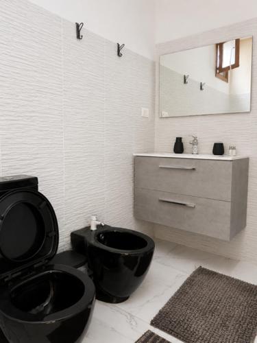 a bathroom with a black toilet and a sink at Monolocale in un piccolo paradiso in Tramatza