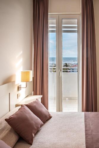a bedroom with a bed with a view of the ocean at Hotel Esplanade in Marina di Pietrasanta