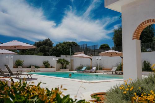 a swimming pool with chairs and umbrellas next to a building at Castellinaria Country Resort in Castellana Grotte
