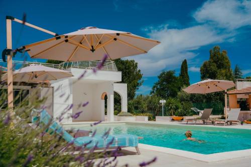 a woman swimming in a pool with two umbrellas at Castellinaria Country Resort in Castellana Grotte