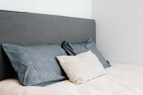a bed with blue pillows and a gray headboard at The Dune gate in Zandvoort
