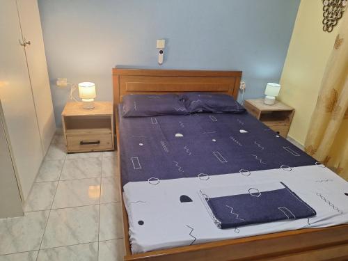 a bed with a blue comforter and two night stands at Vangel Garden in Agios Nikolaos
