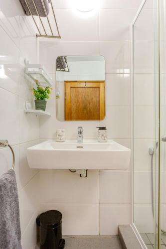 a white bathroom with a sink and a mirror at Beachfront Bliss in Cape Town