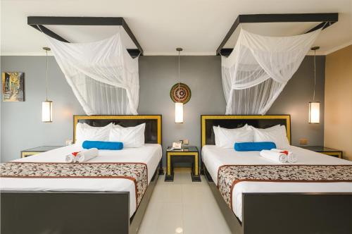 two beds in a room with white and blue at Canary Kendwa Beach Resort in Kendwa