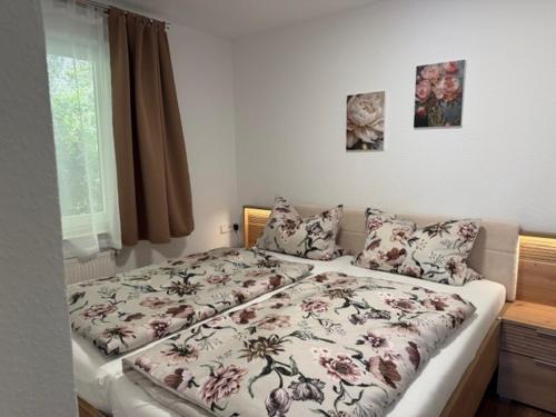 a bedroom with a bed with a floral bedspread and pillows at Ferienwohnung Hopfentraum in Alpirsbach
