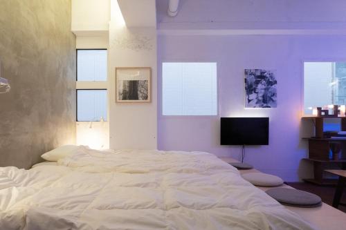 a large white bed in a bedroom with windows at apartment hotel Tasu Toco room 2 in Kichijōji