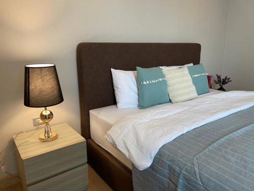 a bed with blue and white pillows and a lamp at CONDO UNIT With BALCONY in Bangkok