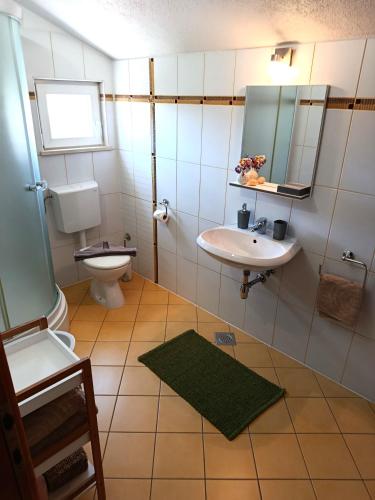 a bathroom with a sink and a toilet and a mirror at Apartments Paloc - Green in Bol