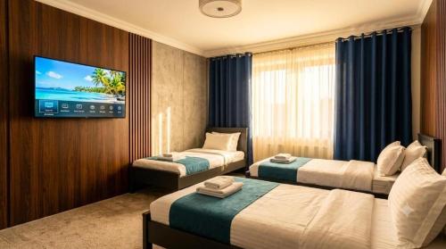 a hotel room with two beds and a flat screen tv at Hotel Usmoon in Tashkent