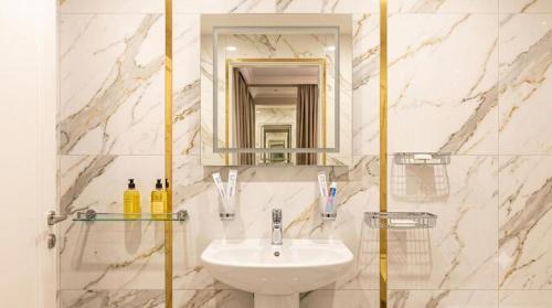 a white bathroom with a sink and a mirror at Hotel Usmoon in Tashkent