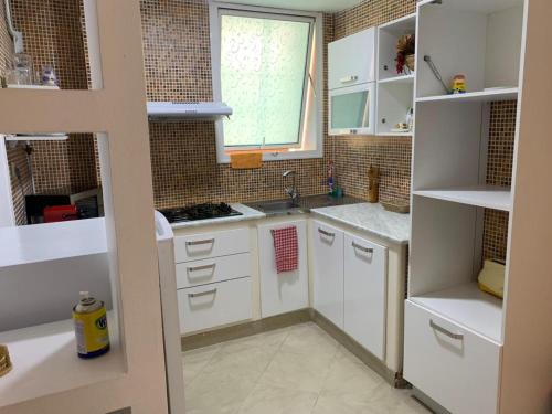 a small kitchen with white cabinets and a window at Appartement familial centre de Hydra in Hydra