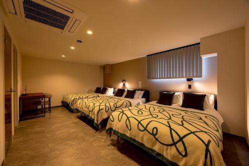 a hotel room with three beds and a desk at Open記念セール!! AXIS STAY asahikawa36 旭川街中に佇むLuxury Stay in Asahikawa