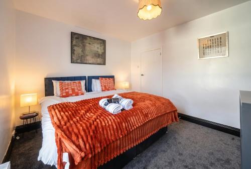 a bedroom with a bed with a orange blanket at Modern Bletchley home with stylish decor in Bletchley