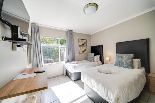 a hotel room with two beds and a desk at 18 Goethe in Secunda
