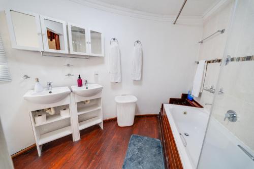 a white bathroom with two sinks and a shower at 18 Goethe in Secunda
