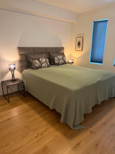 a bedroom with a large bed with a green bedspread at Sentrumsnær leilighet Bergen in Bergen