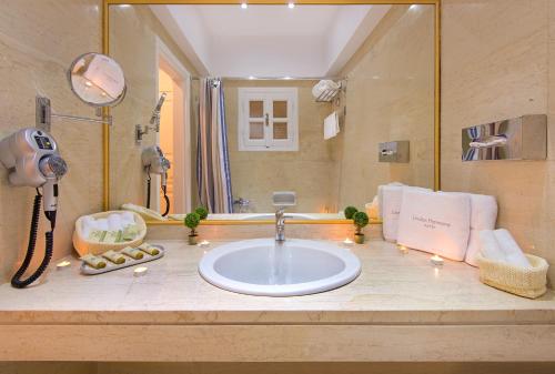 a bathroom with a sink and a large mirror at Lindos Harmony Suites in Lindos