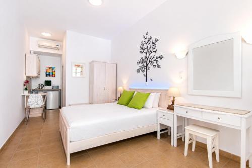 a white bedroom with a white bed and a desk at Lindos Harmony Suites in Lindos