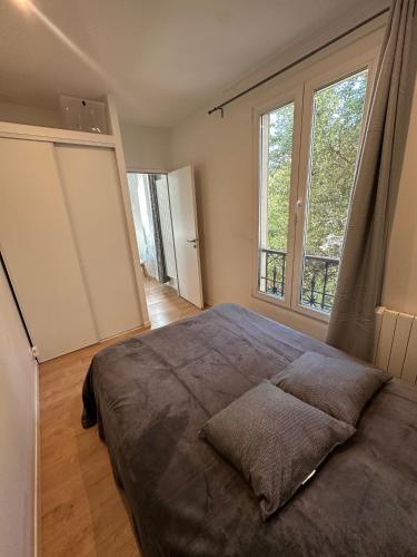 a bedroom with a large bed and two windows at La lumière d'Issy in Vanves