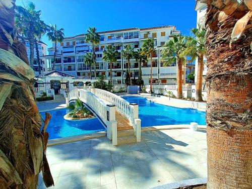a bridge over a swimming pool with a building at Apartament La Mata "FELIZ" in La Mata