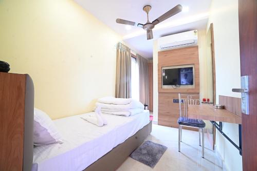 a hotel room with a bed and a desk and a television at Eloras Inn in Siliguri