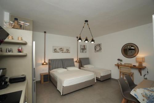 a bedroom with two beds and a table and a desk at Onar Sifnos by the sea in Cherronisos