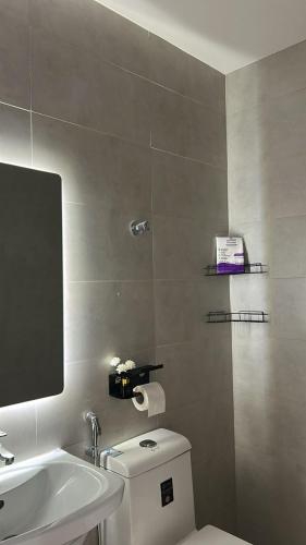 a bathroom with a toilet and a sink and a mirror at Sukoon in Dammam