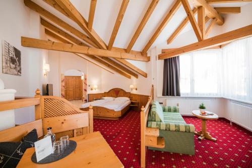 a hotel room with a bedroom and a bed at Hotel Laurin in Dobbiaco