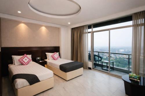 a hotel room with two beds and a large window at Crown Comfortia Hotel Jashore in Jessore