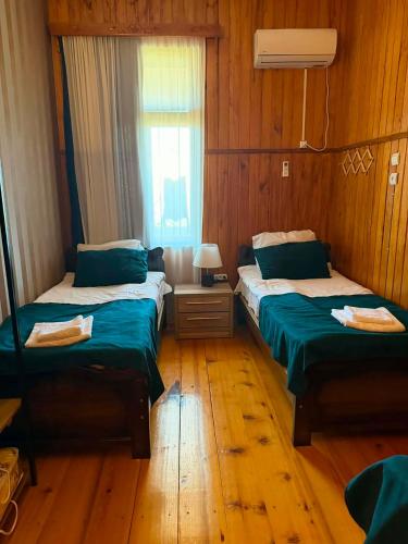 two beds in a room with wooden floors and a window at Baias Wine in Bagdatʼi