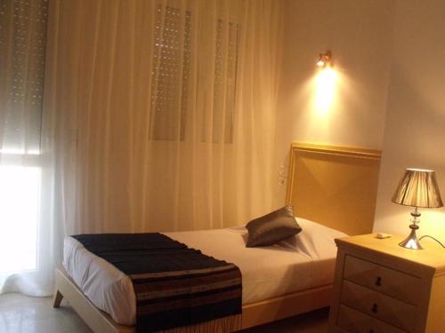 a bedroom with a bed and a lamp and a window at Castilia suites in Tozeur