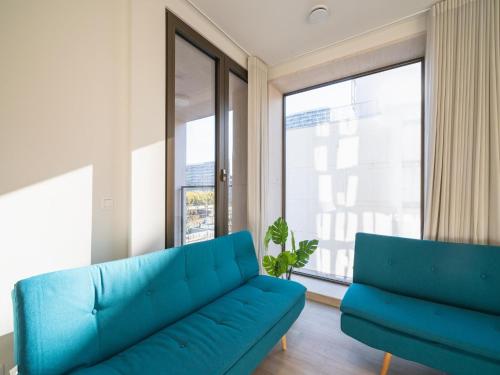 a living room with a blue couch and a large window at City Hideaway with Terrace in Antwerp in Antwerp