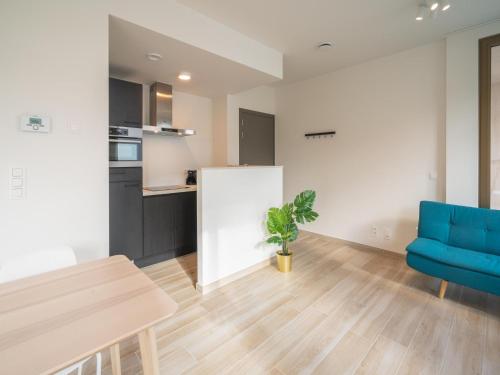 a kitchen and living room with a table and a blue chair at City Hideaway with Terrace in Antwerp in Antwerp
