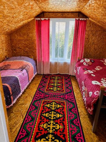 a bedroom with two beds and a rug on the floor at Guest House Dinara in Kaji-Say