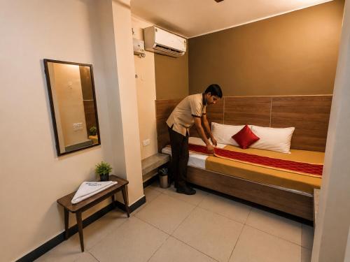 a man making a bed in a hotel room at Nathan's Residency in Tiruchirappalli