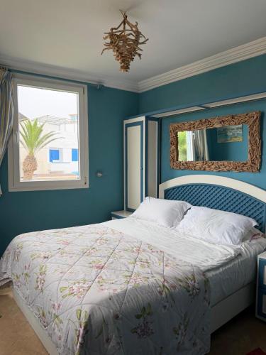 a bedroom with a large bed with a blue wall at Sallys in Mirleft