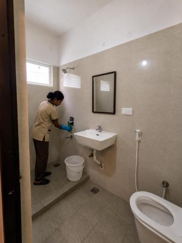 a woman standing in a bathroom with a sink at Nathan's Residency in Tiruchirappalli